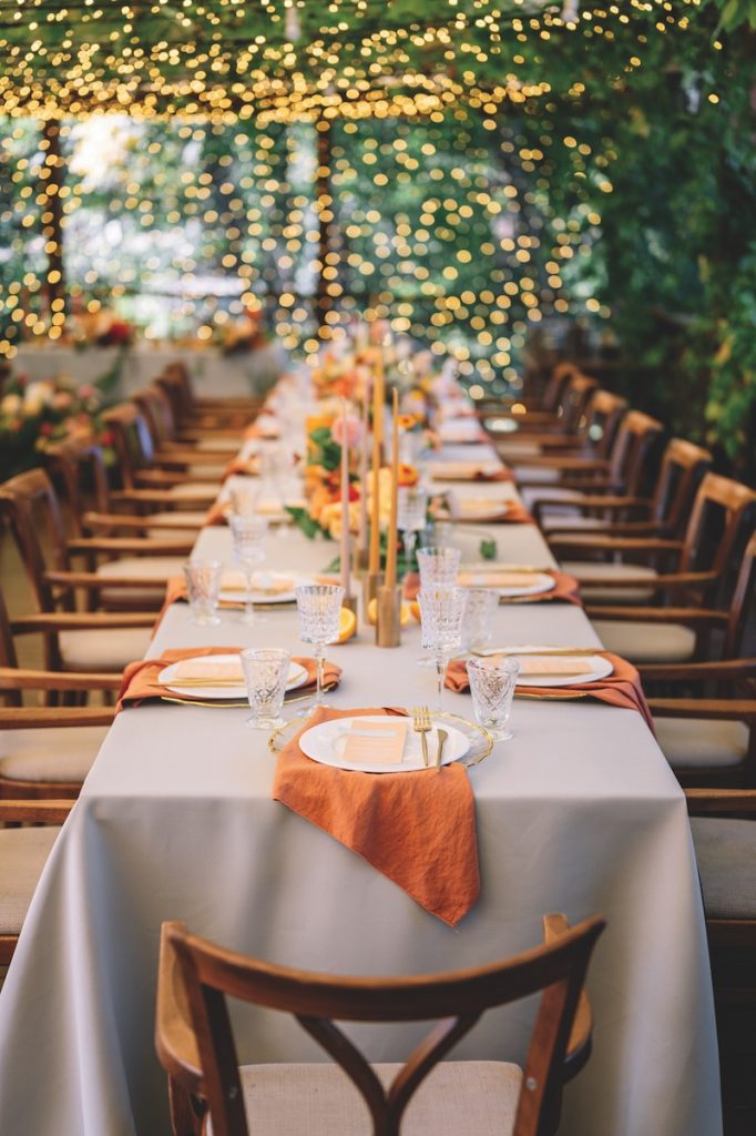 outdoor wedding. long banquet tables with white tablecloths , on the tables are flower arrangements, candles, plates with napkins, glasses and cutlery in autumn style