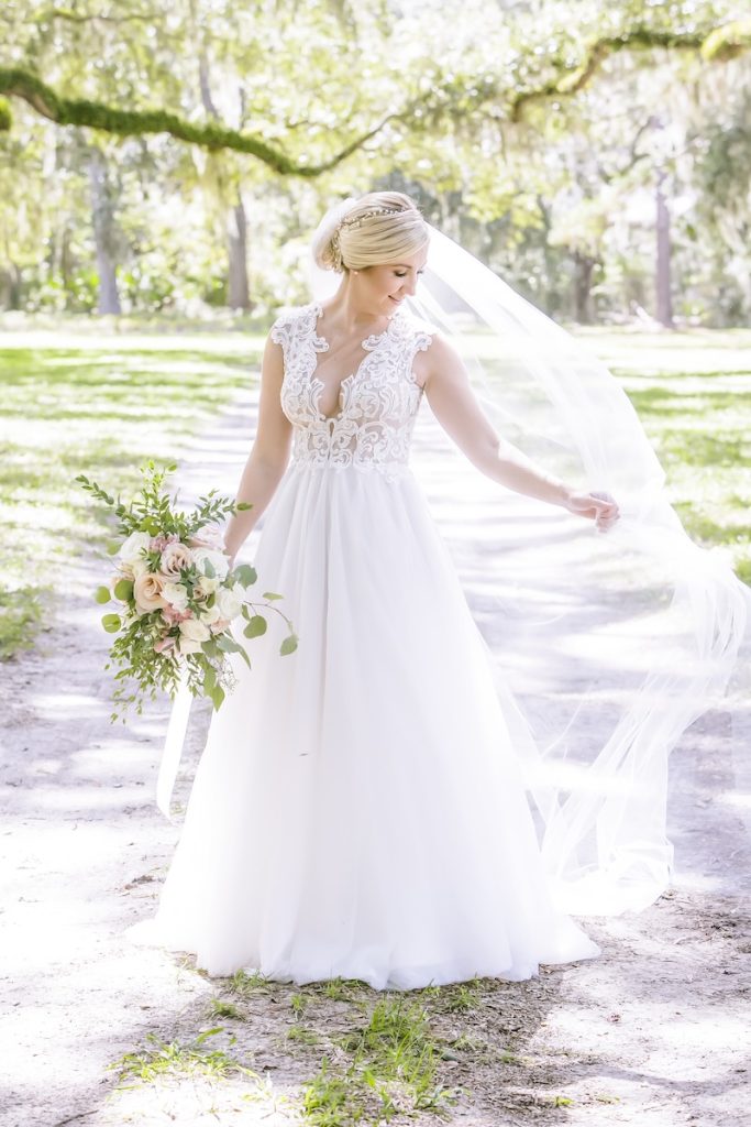 Spring Bride posing outside holding flowers and her veil