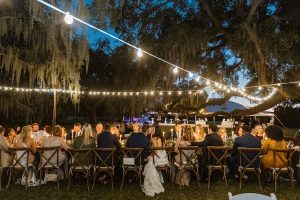 Couple kissing at a large wedding table under lights at night