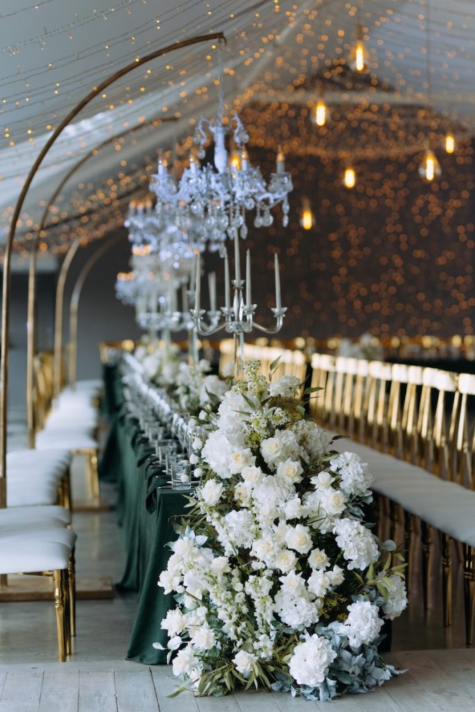 luxury wedding banquet hall. Table decorated for a wedding celebration. Bouquets of white and peach flowers, vintage decor. White bright room, an arch of rose flowers